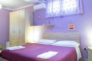 a purple bedroom with a bed with two towels on it at Campi Flegrei House in Naples