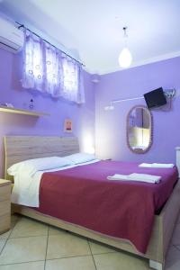 ナポリにあるCampi Flegrei Houseの紫の壁のベッド1台、鏡が備わるベッドルーム1室が備わります。
