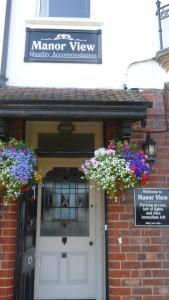drzwi wejściowe ceglanego budynku z dwoma koszami kwiatów w obiekcie Manor View w mieście Whitby
