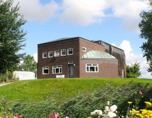 a brick building on top of a grassy hill at Reiterhof Wollesen in Süderlügum