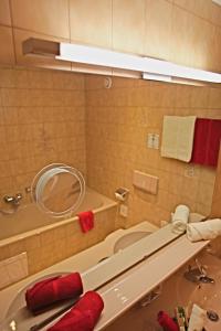 ein Badezimmer mit einer Badewanne, einem Waschbecken und einem Spiegel in der Unterkunft Pension Walserheim in Lech am Arlberg
