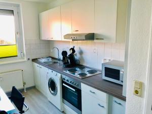 a kitchen with a washing machine and a microwave at Zimmervermietung38 - Mammut 1 in Salzgitter +13 photos