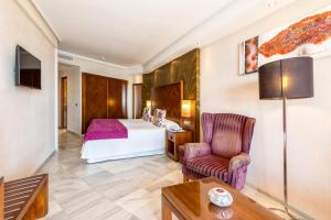 a hotel room with a bed, chair and a lamp at Hotel Balcón de Europa in Nerja