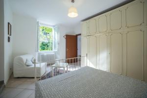 1 dormitorio con 1 cama, 1 silla y 1 ventana en Casa Bertul, en Lezzeno