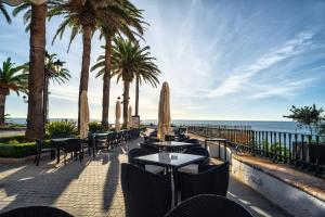 a patio with tables and chairs and the ocean at Hotel Balcón de Europa in Nerja