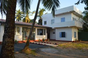 a white house with palm trees in front of it at Villa Whispering Shells in Kalutara