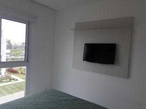 einen Flachbild-TV an einer weißen Wand in einem Schlafzimmer in der Unterkunft Porto de Galinhas - Muro Alto Condomínio Clube in Porto De Galinhas