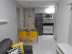 eine Küche und ein Esszimmer mit einem Tisch und gelben Stühlen in der Unterkunft Porto de Galinhas - Muro Alto Condomínio Clube in Porto De Galinhas