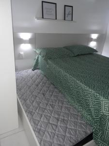 Bett mit einer grünen und grauen Bettdecke und Kissen in der Unterkunft Porto de Galinhas - Muro Alto Condomínio Clube in Porto De Galinhas + 18 Fotos