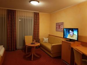 a living room with a couch and a tv at Hotel-Restaurant Fröhlich in Kaiserslautern