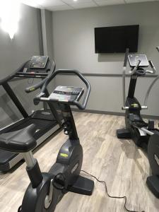 a gym with two exercise bikes and a flat screen tv at The Originals City, Hôtel Le Boeuf Rouge, Saint-Junien in Saint-Junien