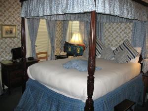 A Cambridge House Inn في كامبريدج: غرفة نوم بسرير مظلة مع لحاف أبيض