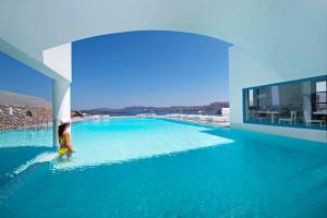 a person standing in the water in a swimming pool at Acroterra Rosa Luxury Suites & Spa in Akrotiri