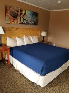 Eunice的住宿－L'Acadie Inn & RV Park，一间卧室配有一张带蓝色毯子的大床
