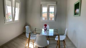 a glass dining room table with white chairs and two windows at Casa Xuncal in Tui