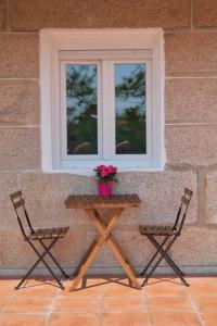 a picnic table and two chairs in front of a window at Casa Xuncal in Tui