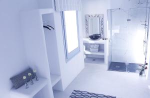 a white bathroom with a shower and a sink at Aegean of Amorgos in Katapola