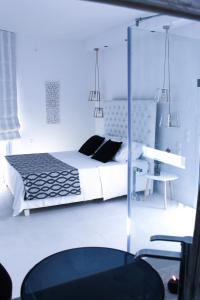 a white bedroom with a bed and a table at Aegean of Amorgos in Katapola