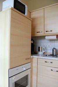a kitchen with wooden cabinets and a microwave at Apartment am Steinweg in Emden