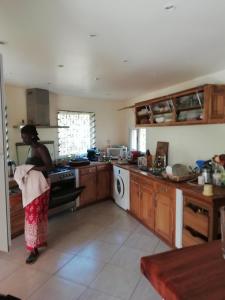 una mujer parada en una cocina preparando comida en Villa Maria en Somone