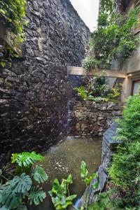 a stone wall with a pond in a garden at Hotel de la Cañada in Córdoba