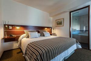 a hotel room with a large bed and a bathroom at Hotel de la Cañada in Córdoba