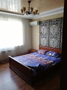 um quarto com uma cama com um edredão azul e uma janela em Daily rent Apartments 4 em Ivano-Frankivsʼk