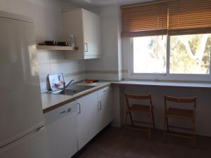 eine Küche mit weißen Schränken, einem Waschbecken und einem Fenster in der Unterkunft Cabo de Gata Oasis Retamar II in Almería