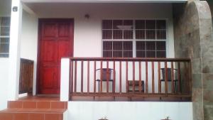 a red door and two chairs on a balcony at Habitat Apartments in Gros Islet