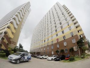 two large buildings with cars parked in a parking lot at Cozy Studio near Beaches with NetFlix and Pool in Mactan
