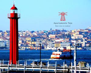 a red lighthouse and a boat in a body of water at Apartamento Tejo in Cacilhas