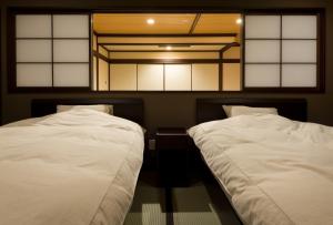 2 camas en una habitación con sábanas blancas en Hokuriku Yamashiro Onsen Hotel Kikyou, en Yamashiro