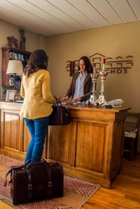Los Ponchos Hotel في إل كالافاتي: امرأة تقف في مكتب الاستقبال مع أمتعتها
