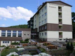 ein Hotel mit einem Innenhof mit Tischen und einem Gebäude in der Unterkunft Apartmenthotel-Harz in Friedrichsbrunn