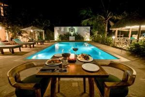 馬拉利庫蘭的住宿－Flamingo Boutique Hotel & Ayurvedic spa，游泳池旁带餐盘的桌子