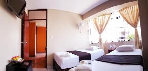 een kamer met 2 bedden, een tv en een raam bij Starlight Inn in Pisco