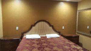 a bedroom with a bed with a large headboard and a mirror at Central Inn Motel in Los Angeles