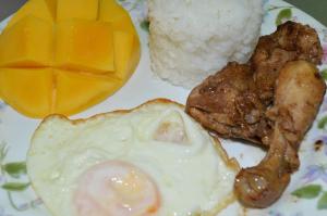 a plate of food with an egg and meat and rice at Bluewaves Westcliff Villa in Boracay
