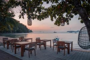 a group of tables and chairs next to the water at The Cove in Panwa Beach