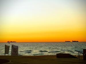 zachód słońca nad oceanem z znakiem na plaży w obiekcie Spat Hotel Ashdod w mieście Aszdod