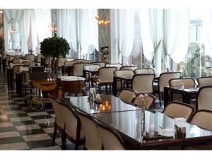 un comedor con mesas, sillas y ventanas en Koyo Grand Hotel, en Sendai