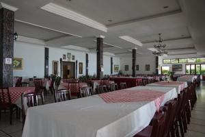 a dining room with tables and chairs with red and white tablecloths at Toledo Inn in Tuktuk Siadong