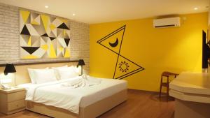 a bedroom with a white bed and a yellow wall at Nite & Day Laguna Bintan in Tanjung Pinang