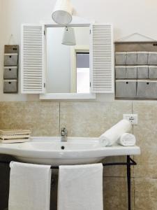 un bagno con lavandino, specchio e asciugamani di Villa Erminia a Canicattini Bagni
