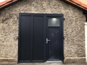 une porte noire sur le côté d'un bâtiment dans l'établissement Le Studio de Lucie, à Villeurbanne