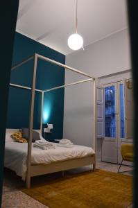 ein Schlafzimmer mit einem Himmelbett und einer blauen Wand in der Unterkunft Dimora San Camillo in Catania