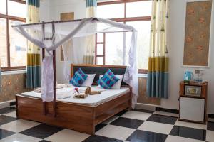 sypialnia z łóżkiem z baldachimem i podłogą wyłożoną szachownicą w obiekcie Mocco Beach Villa w mieście Kendwa