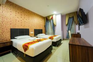 a hotel room with two beds and a television at AB Inn Hotel in Kulai +34 photos