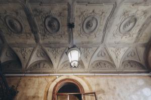 um quarto com um tecto com um lustre em Gregorini Bingham Art Luxury Suites em Bolonha