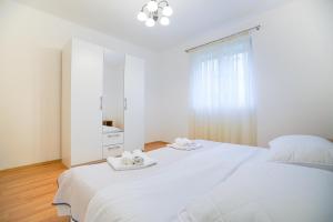 ein weißes Schlafzimmer mit einem großen Bett und zwei Handtüchern in der Unterkunft Roko in Zadar